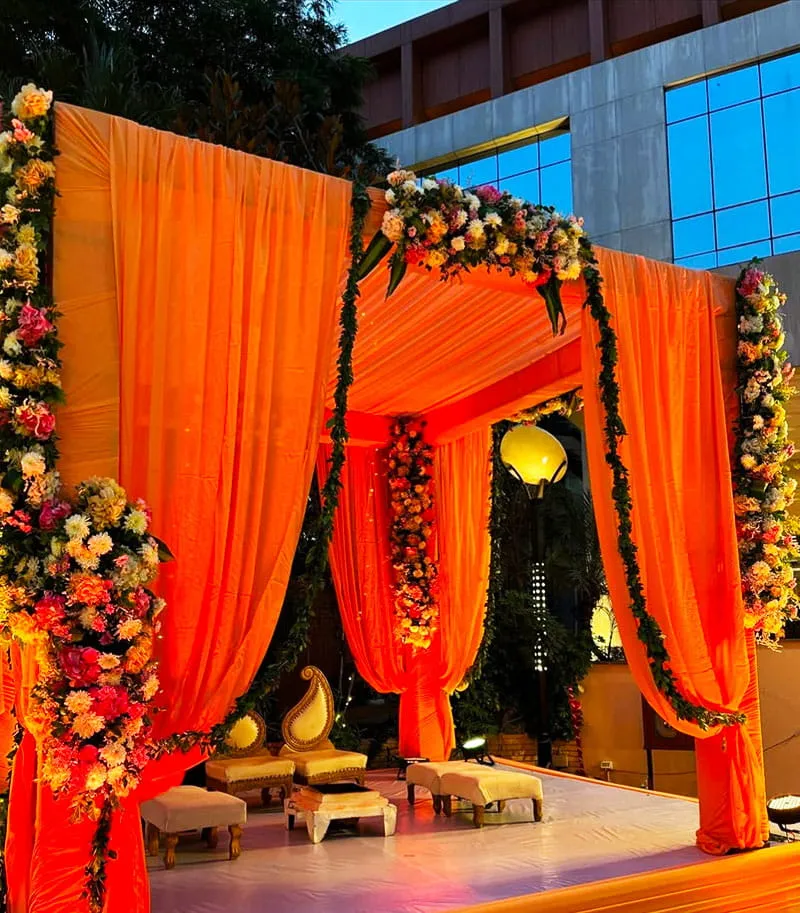 Decorated Wedding Mandap with Orange Drapes and Floral Arch — Hotel Aketa Dehradun